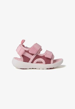 Sandale en maille rose avec des brides réglables en Velcro et une semelle en caoutchouc blanche. Comprend des découpes pour la respirabilité et une languette arrière pour faciliter l'enfilage.