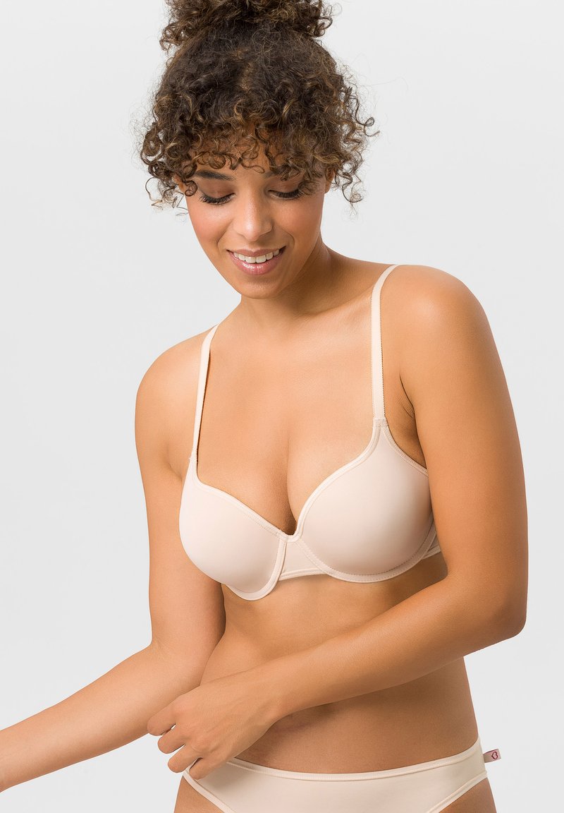 Beige geformter BH mit verstellbaren Trägern, glatter Textur, Bügelunterstützung und einem leichten Glanz. Enthält ein Logo-Etikett am Band.