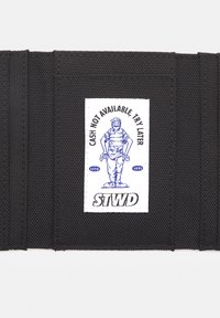 Black fabric strap with textured surface. White label features blue illustration of a person and text "CASH NOT AVAILABLE TRY LATER" and "STWD."
