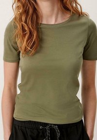Olivengrøn kortærmet t-shirt med rund halsudskæring, lavet af glat stof, tætsiddende design, parret med sorte shorts med snoretræk.