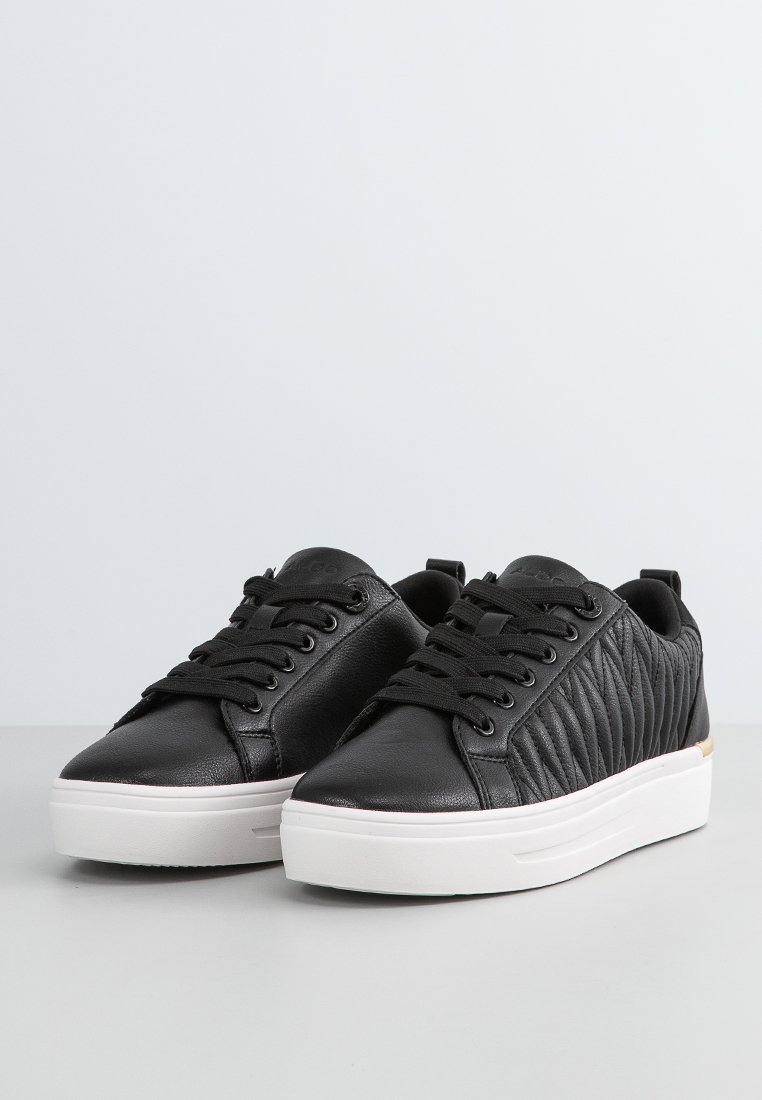 Baskets noires avec un design matelassé texturé d'un côté, en cuir lisse de l'autre, et semelles en caoutchouc blanches. Fermeture à lacets.