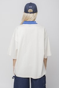 Prevelik krem T-shirt z ovratnikom v modrih črtah, z kratkimi rokavi in sproščenim krojem, združen z mornarsko modro kapo.