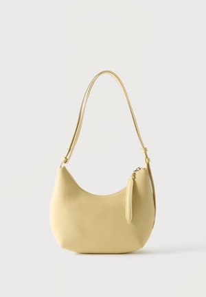 Petit sac à épaule en cuir jaune pâle avec bandoulière réglable et fermeture éclair supérieure sur fond uni.