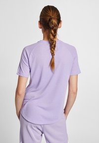 Ljuslila T-shirt med kort ärm och rundad nederkant, med raglanärmar, gjord av textilerad tyg, tillsammans med matchande lavendelfärgade byxor.