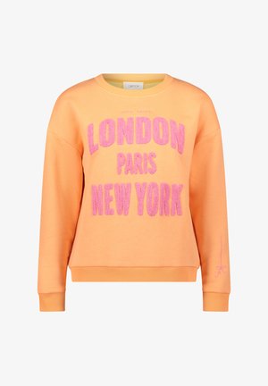 Orangener Pullover mit auffälligem, flauschigem pinkem Text, der "LONDON PARIS NEW YORK" liest, und einem kleinen pinken Akzent auf dem Ärmel.