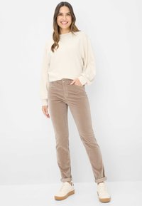 Beige sweatshirt med lange ærmer, parret med lysebrune corduroybukser og cremede sneakers med en tekstureret sål.