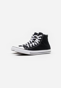 Czarne sneakersy za kostkę wykonane z płótna, z białymi gumowymi podeszwami, białym sznurowanym zapięciem oraz kontrastującymi detalami zszycia.