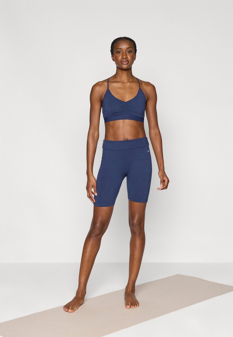 Αθλητικό cropped τοπ σε ναυτικό μπλε και σορτς με ψηλή μέση από ελαστικό ύφασμα. Διαθέτει λεπτές τιράντες, ραμμένο μπροστινό μέρος με λεπτομέρειες και λεία υφή.