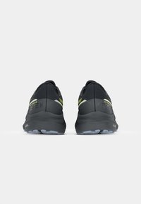 Zwarte hardloopschoenen met een gestructureerde bovenkant, voorzien van een waterdichte Gore-Tex laag, heldergele accenten en een gevoerde Zool met grip.