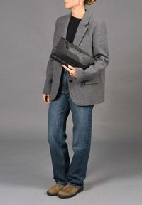 Blazer de lana gris, bolso de cuero negro con detalles de remaches, vaqueros oscuros y zapatos marrón claro. Diseño simple y estructurado con materiales en contraste.