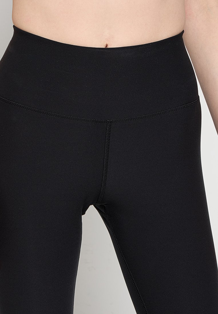 Leggings neri con vita alta, realizzati in materiale elasticizzato. Presentano cuciture piatte e una texture liscia, ideali per un indosso confortevole.