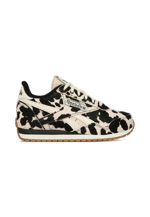 Niskie buty sportowe Reebok z czarno-białym wzorem w krowie łatki, białe sznurowadła, beżowa wkładka i gumowa podeszwa z boku.