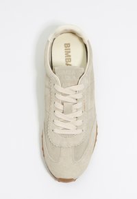 Beige suède sneaker met een ronde neus, ton-sur-ton stiksels en platte veters. Voorzien van een rubberen buitenzool en een reliëf merkdetail op de tong.
