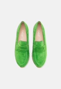 Gröna mockaloafers med en moccasin-design, med en sömmad accenterad vamp och en gummisula. Inga ytterligare mönster eller hårdvara synliga.