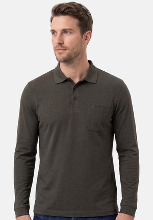 Uomo con capelli castani corti che indossa una polo a maniche lunghe verde scuro con una tasca sul petto, che guarda leggermente verso sinistra su uno sfondo semplice.