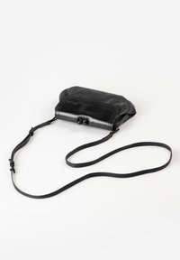 Black leather crossbody bag with a long adjustable strap, rounded clasp closure, and slightly gathered top on a white background.