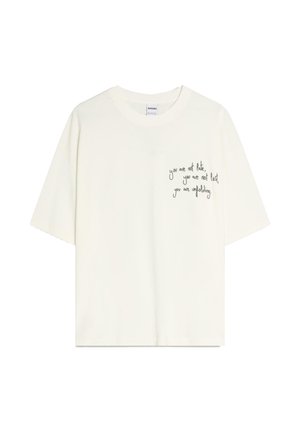 White short-sleeve t-shirt with round neckline and black handwritten text on left chest reading, "you are not late, you are not lost, you are unfolding."