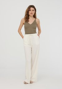 Top a canotta a coste d'olive con scollatura a V, abbinato a pantaloni larghi color crema con fascia elastica in vita e dettaglio con cordoncino.