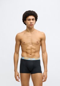 Mustad Nike bokserpüksid sinise vöökohaga, millel on oranž logo. Valmistatud venivast materjalist, istuva lõike ja keskmise reie pikkusega.