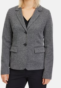 Grå tweedblazer med slagkrage, två framfickor och dubbelknäppning. Texturerad tyg med ett subtilt mönster.