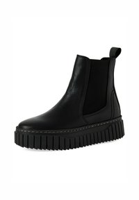 Botín Chelsea negro de cuero con paneles laterales elásticos, tira de agarre y suela de goma gruesa y estriada. Costuras detalladas alrededor del borde.