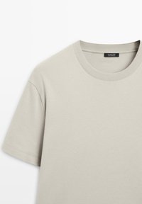 T-shirt beige à manches courtes en coton avec col rond côtelé et une étiquette Massimo Dutti noire à l'intérieur du col.