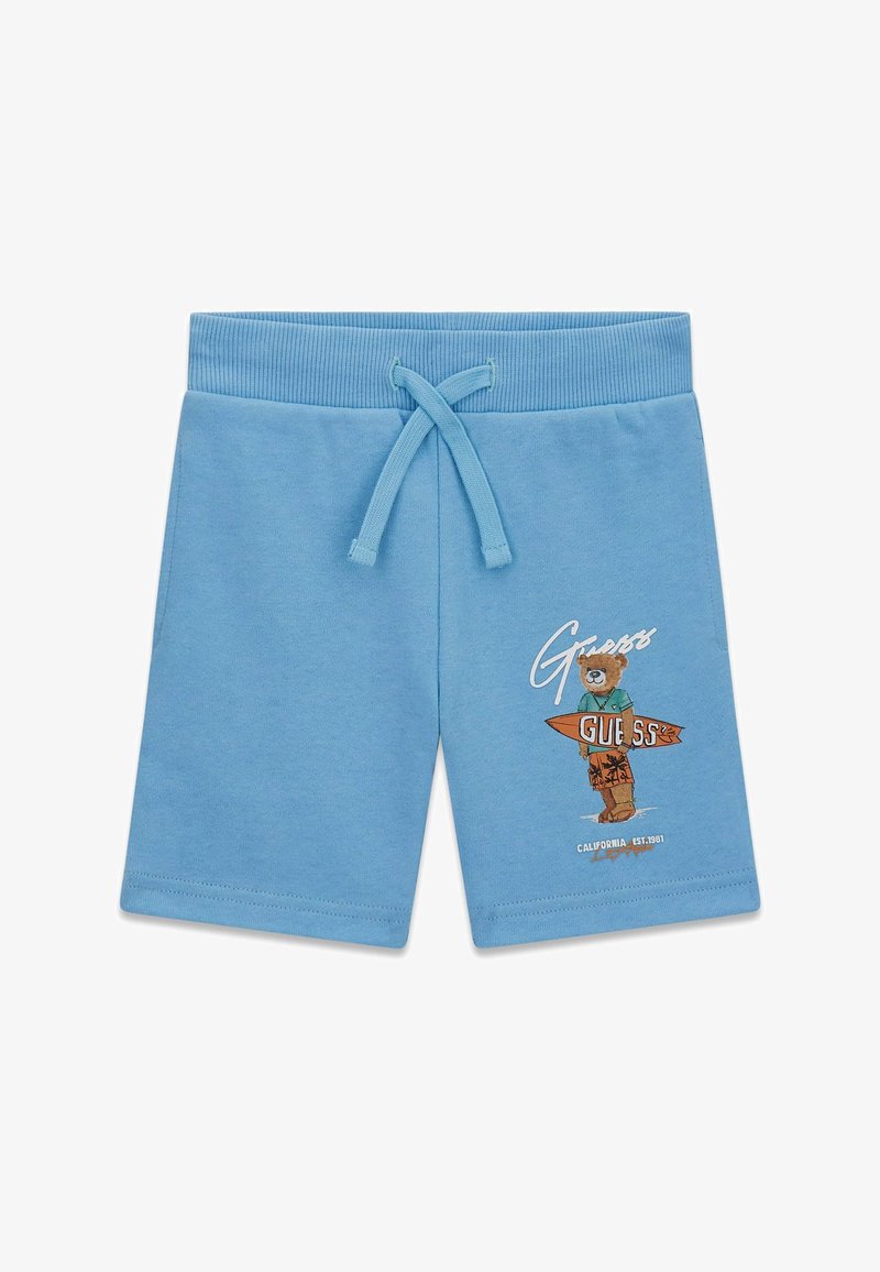 Pantalones cortos para niños de color azul claro con cintura ajustable con cordón y gráfico de un oso sosteniendo una tabla de surf con la palabra "Guess" en la pierna derecha.