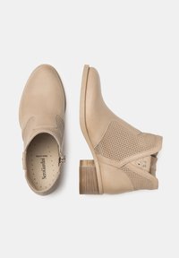 Bottines beige avec cuir lisse et accents en mesh. Elles présentent un talon empilé, des panneaux élastiques sur les côtés et des détails de couture.
