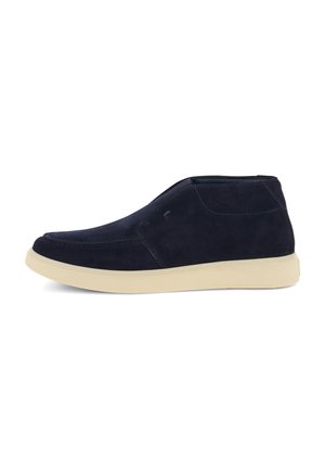 Chaussure montante en daim bleu marine avec semelle en caoutchouc crème, modèle sans lacets et coutures visibles sur la tige.