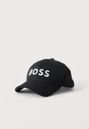 Casquette de baseball noire avec visière courbée et texte brodé blanc "BOSS" sur le panneau avant sur fond blanc.
