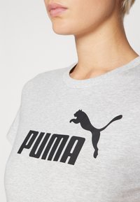 Hallhalli halline T-särk, millel on suur must "PUMA" logo ja hüppava musta puma graafika. Klassikaline ümmargune kaelus. Sile tekstuur.