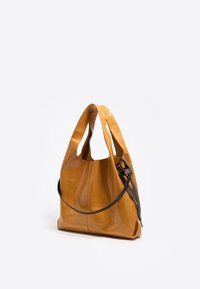 Bolso hobo de cuero amarillo con una textura suave, que presenta una sola correa oscura para el hombro y un diseño relajado. Acentuado con líneas de pliegue.
