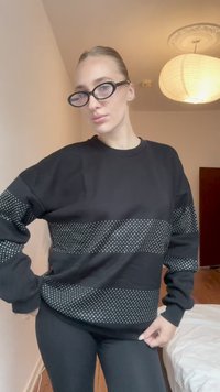 Čierny mikina s bodkovaným vzorom cez hrudník a rukávy. Podkrčovaný výstrih, voľný strih, textúrovaná tkanina, nosená s čiernymi legínami.