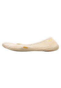 Beige mesh platta med en flexibel design, Vibram-sula för grepp, texturerad ovandel och framträdande logotyp nära hälen.