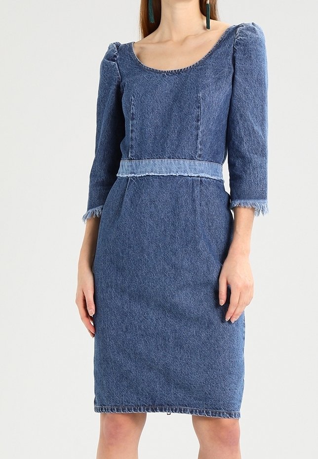 Denimmekko, jossa on tiivis siluetti, kolmanneksen hihat, pyöreä kaula-aukko ja fringet korostukset hihoissa ja helmakohdassa.