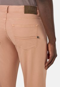 Jeans rosa chiaro realizzati in tessuto morbido, dotati di tasche posteriori, una patch in pelle con il marchio alla vita e una vestibilità a gamba dritta.
