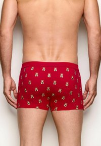 Red boxer briefs covered in small teddy bear patterns. Soft fabric with a snug fit, featuring an elastic waistband and smooth texture.