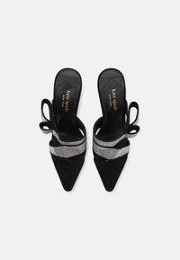 Must musta slingback-kreenid, millel on terav varvas ja hõbedane dekoratiivne riba. Kingadel on madal konts ja kangast kaunistus.