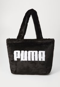 Sac fourre-tout en fausse fourrure noire avec une texture pelucheuse, ornée d'un logo "PUMA" blanc bien visible à l'avant et de doubles poignées en tissu.