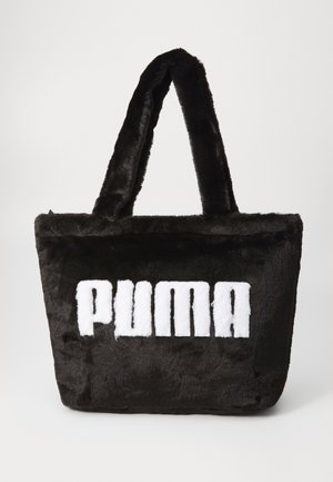 Bolso tote de piel sintética negra con textura suave, que presenta un destacado logo blanco de "PUMA" en la parte frontal y asas de doble tela.