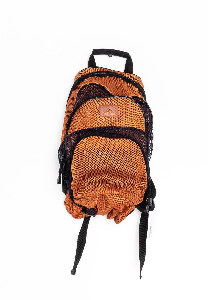 Orange och svart Adidas mesh ryggsäck med flera dragkedjedelar och svarta justerbara remmar på en vit bakgrund.
