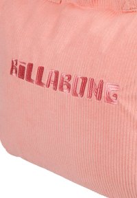 Różowa torba z korduroju o teksturowej powierzchni, z logo "Billabong" w nieco ciemniejszym odcieniu, wyhaftowanym wyraźnie z przodu.
