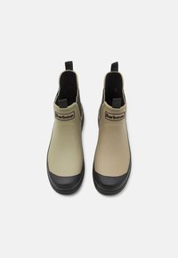 Beige waterproof ankle boots with black rubber soles, featuring a smooth finish, elastic side panels, and a branded tab on the front.