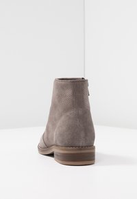 Gray suede ankle boots with perforated design, rounded toe, and low stacked heel. Back view shows a smooth finish and subtle stitching details.