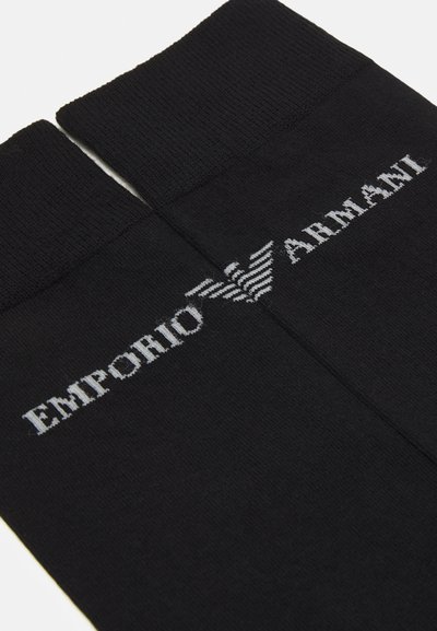 Schwarze Socken aus Baumwollmischung mit gerippten Bündchen. Verfügt über das weiße gestickte Logo "Emporio Armani" und das Adleremblem auf jeder Socke.