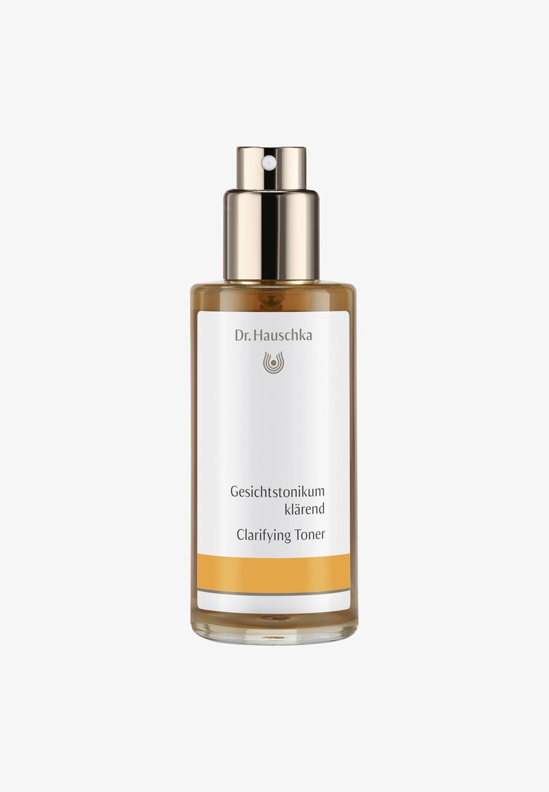 Bouteille en verre transparent avec une pompe et un capuchon métalliques. L'étiquette comporte un fond blanc, du texte noir et une ligne d'accent jaune à la base.