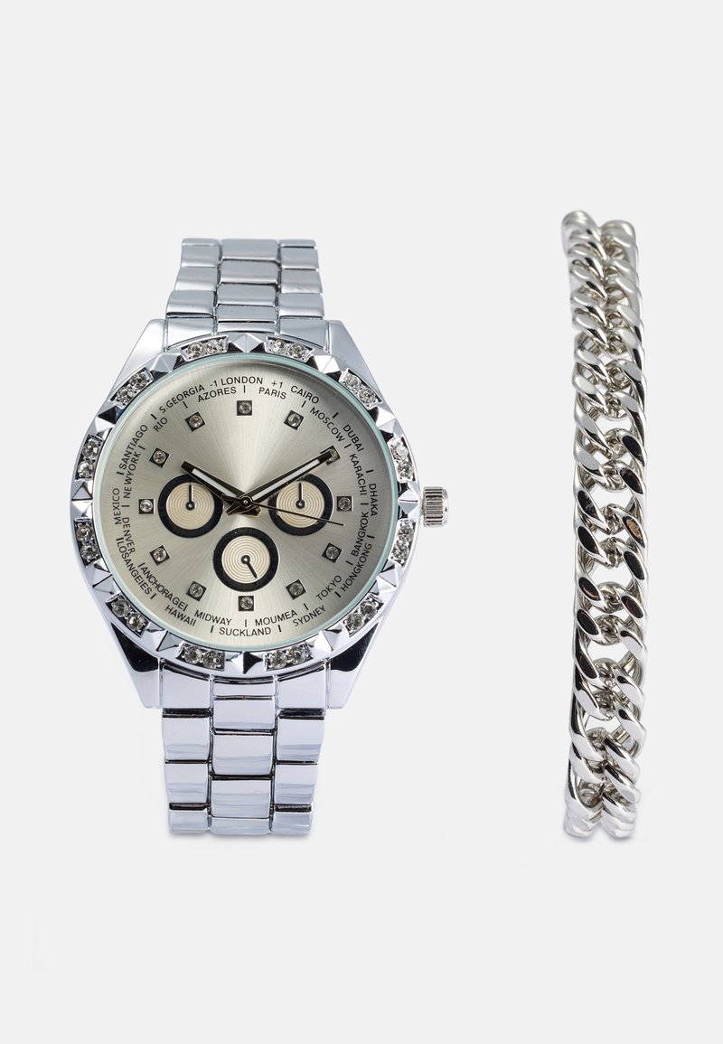 Zilveren roestvrijstalen horloge met een metallic grijze wijzerplaat, voorzien van drie sub-dials en kristalaccenten, gecombineerd met een zilveren schakelarmband.