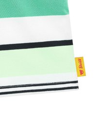 Tejido a rayas con colores verde, blanco y negro, y una textura suave. Incluye una etiqueta amarilla con un logo en la esquina inferior derecha.