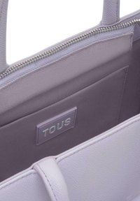 Borsa tote color lilla chiaro, esterno testurizzato, fodera liscia, cerniera argentata, presenta un'etichetta con marchio all'interno. Design semplice e funzionale.