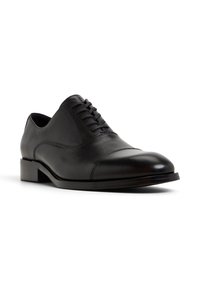 Scarpa da uomo in pelle nera con finitura liscia, punta tondeggiante e sei paia di abhole. Presenta un tacco basso impilato e una tomaia testurizzata.